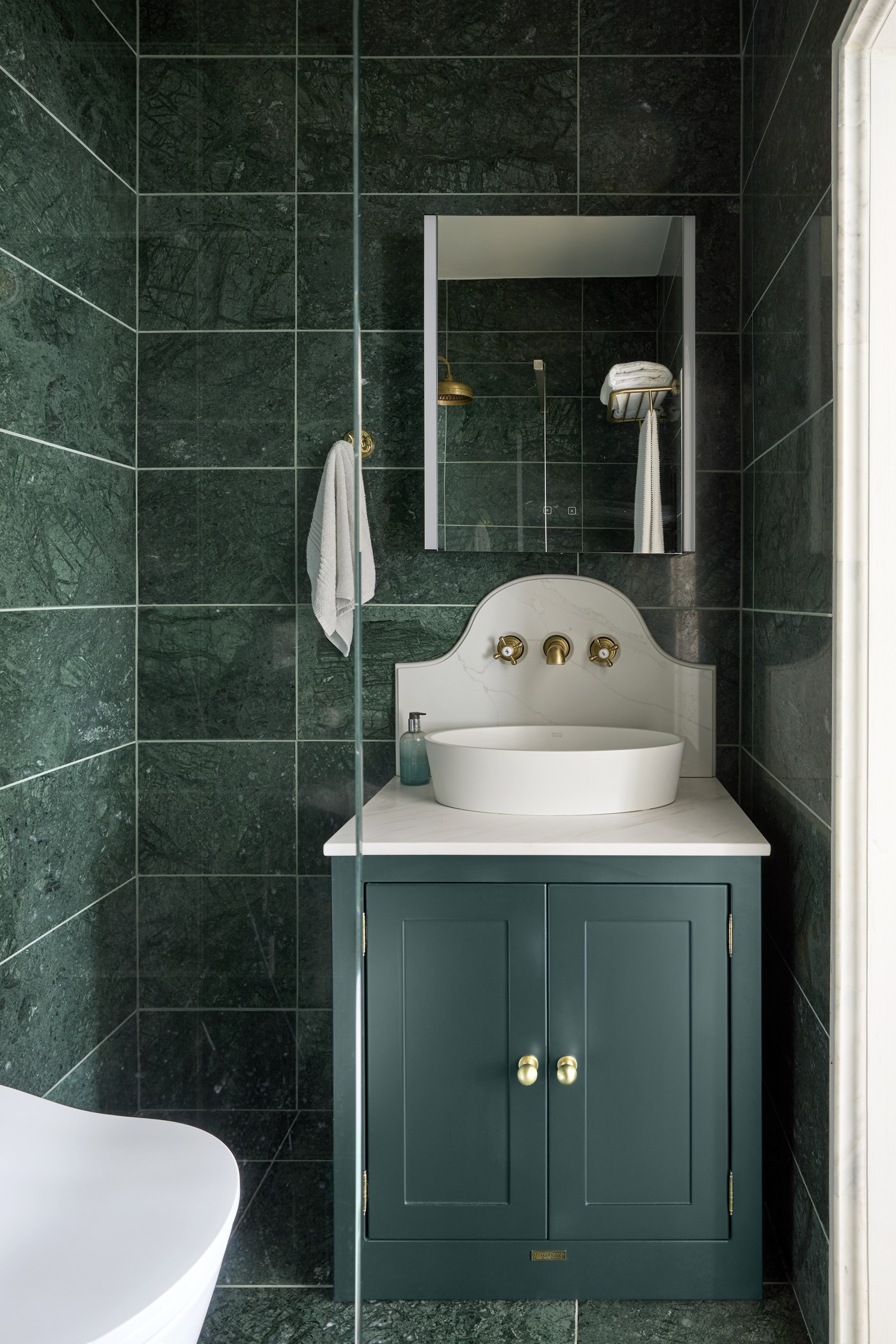 Green marble cloakroom with a scalloped basin and painted vanity at Achilles Road