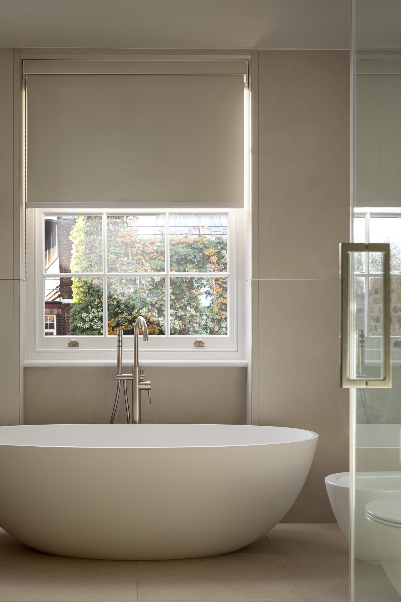 Freestanding bath and brass floor-standing tap beneath a replacement sash window at Brompton Square