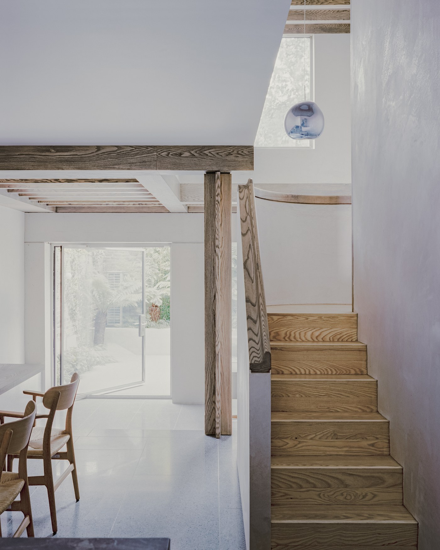 Caithness Road W14 — ash staircase rising beside a timber post and beam, with the garden doors beyond