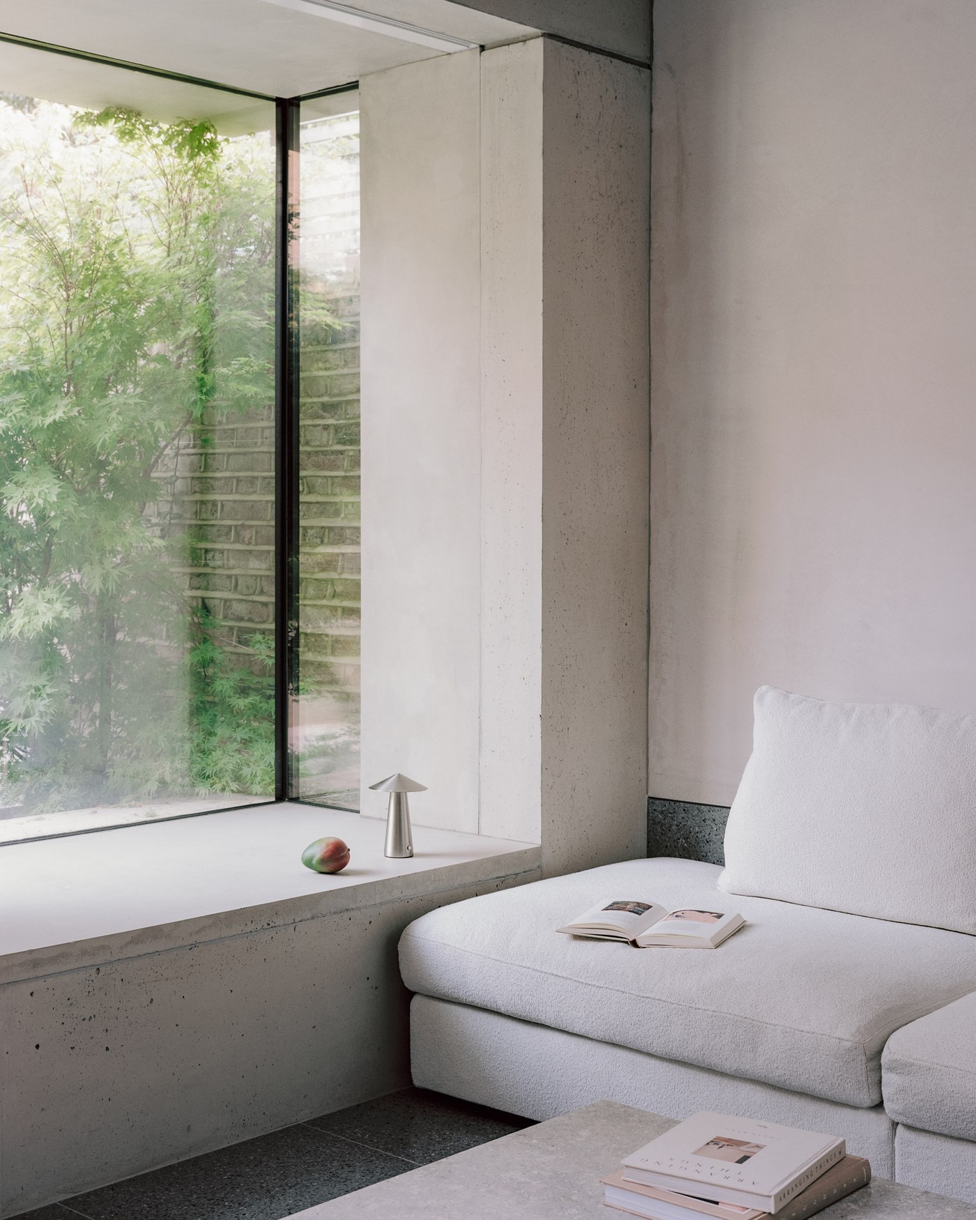 Caithness Road W14 — window seat set into a deep reveal, with frameless glazing turning the corner to the garden planting