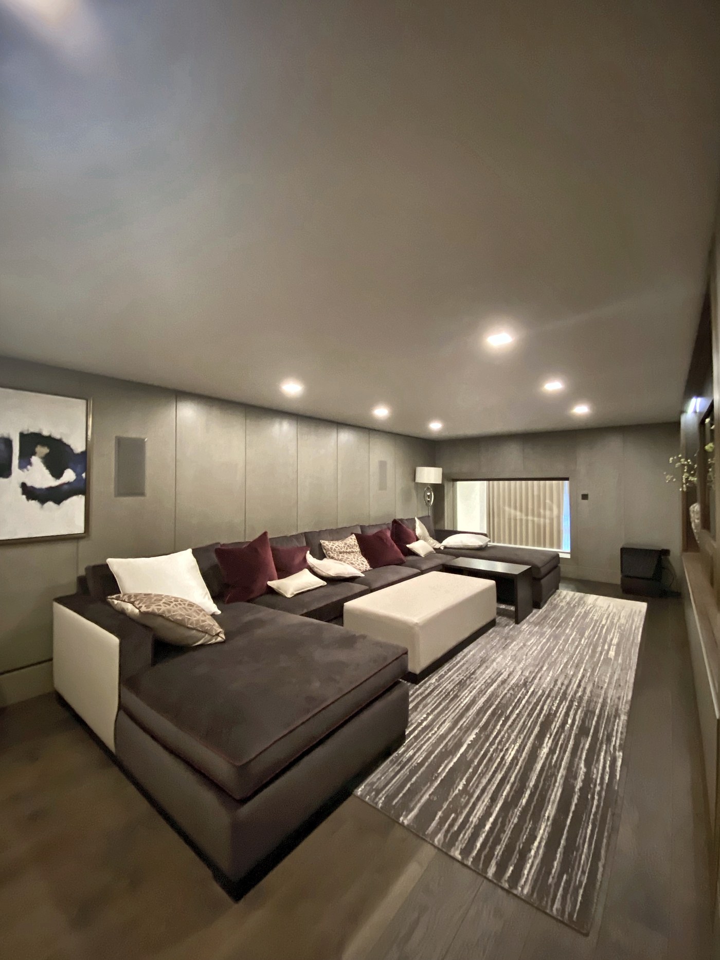 Media room at Connaught Place with built-in banquette seating and a fabric-lined wall