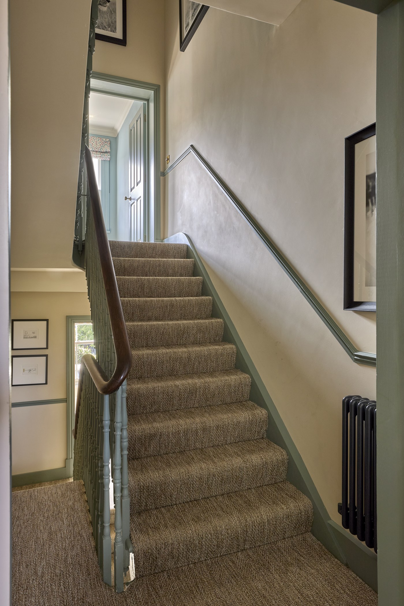 Staircase at Melrose Gardens rising from the hall, with a new runner, painted strings and a dark timber handrail